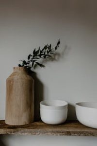 A minimalist kitchen setup featuring a wooden vase with greenery and two white ceramic bowls