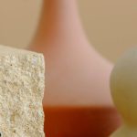 Elegant minimalist still life featuring sculptural vases and a textured stone cube.