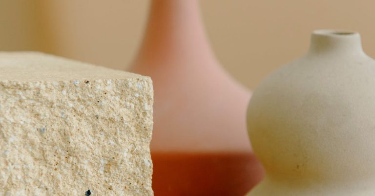 Elegant minimalist still life featuring sculptural vases and a textured stone cube.