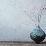 Vase en céramique artisanale émaill posé sur une table en bois, dans une ambiance naturelle et minimaliste.