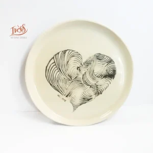 Assiette en céramique artisanale Ixèsos U Ligame avec cœur dessiné en lignes imbriquées, façonnée à la main.